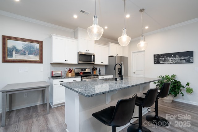 kitchen with an island with sink, white cabinets, and stainless steel appliances