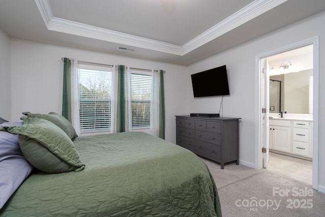 bedroom featuring ornamental molding, a tray ceiling, ensuite bath, and light colored carpet