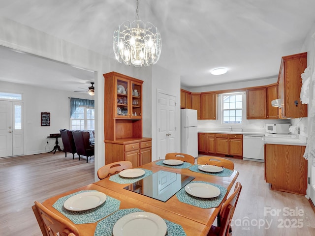 dining space featuring light hardwood / wood-style flooring, ceiling fan with notable chandelier, and sink