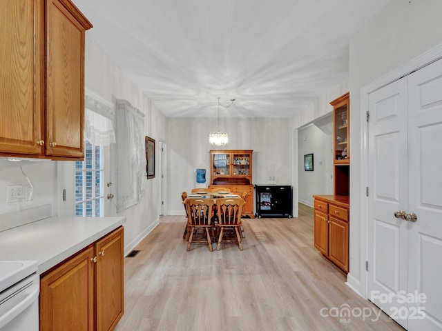 kitchen featuring range, a chandelier, hanging light fixtures, and light hardwood / wood-style floors