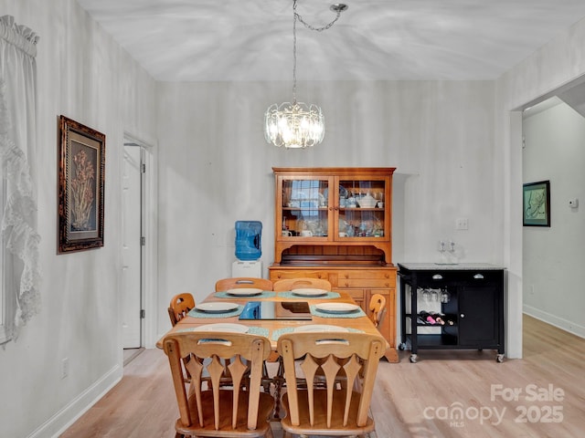 dining space featuring light wood-type flooring and an inviting chandelier