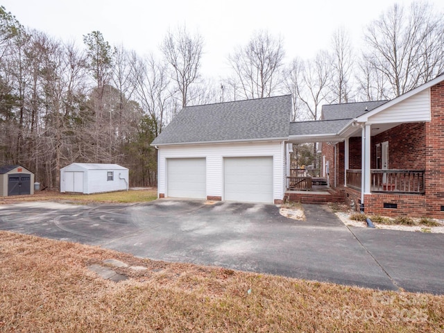 exterior space with covered porch, a garage, and a storage unit