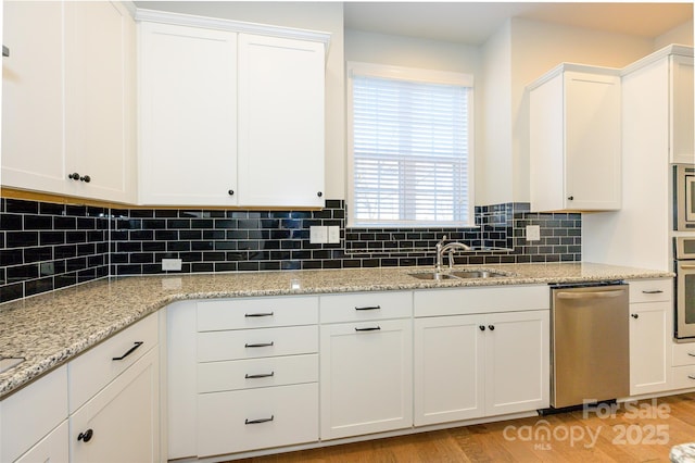 kitchen featuring stainless steel appliances, white cabinets, a sink, and tasteful backsplash