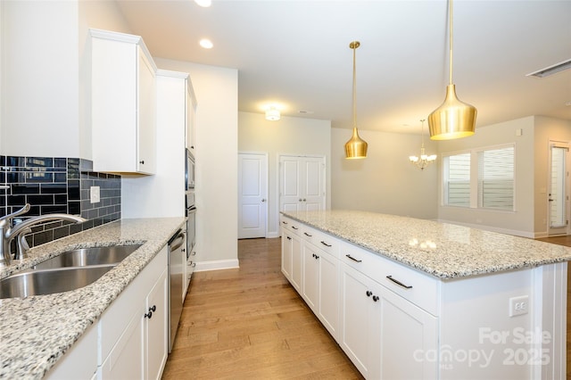 kitchen featuring tasteful backsplash, visible vents, light wood-style flooring, appliances with stainless steel finishes, and a sink