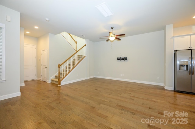 unfurnished living room featuring recessed lighting, light wood-style floors, ceiling fan, baseboards, and stairs