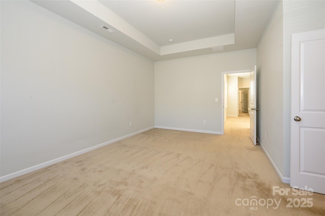 unfurnished room featuring light carpet, a tray ceiling, visible vents, and baseboards