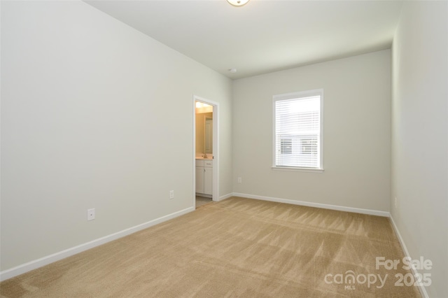 spare room featuring light carpet and baseboards