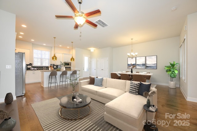 living room featuring recessed lighting, visible vents, wood finished floors, baseboards, and ceiling fan with notable chandelier