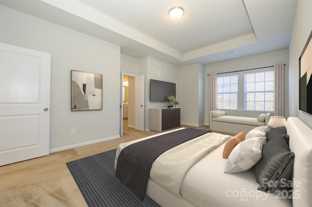 bedroom with a raised ceiling, light carpet, and baseboards