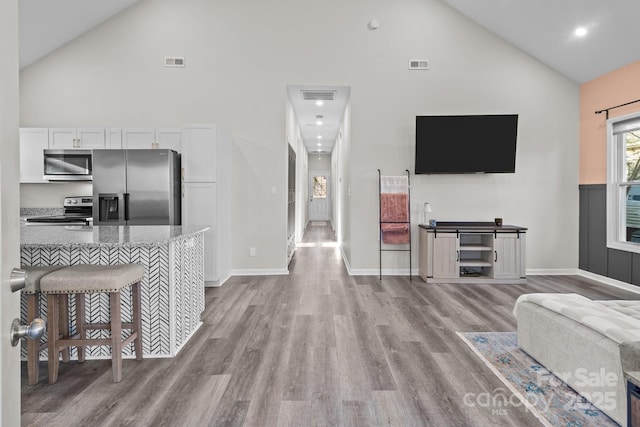 living room with light hardwood / wood-style flooring and high vaulted ceiling