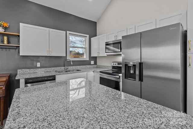 kitchen featuring white cabinetry, sink, appliances with stainless steel finishes, and vaulted ceiling