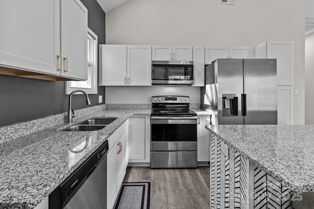 kitchen featuring white cabinets, appliances with stainless steel finishes, light stone counters, and sink