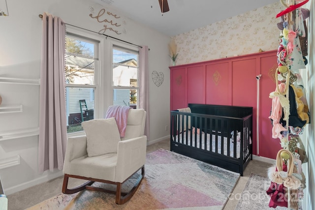 bedroom featuring ceiling fan, light colored carpet, and a nursery area