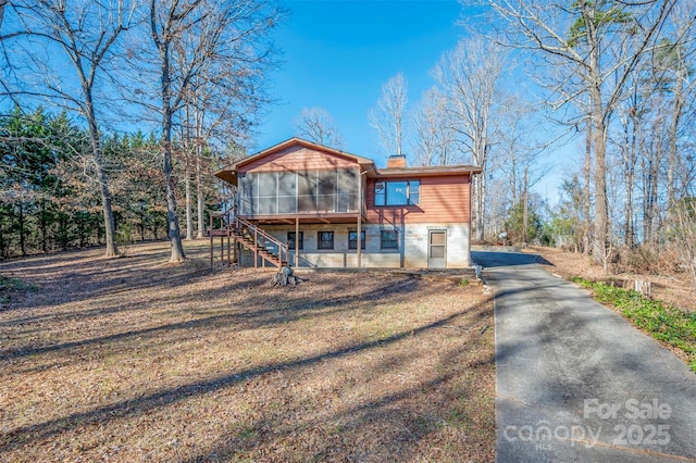 view of front of house featuring a sunroom and a front yard