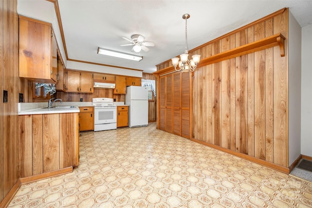 kitchen featuring pendant lighting, wood walls, white appliances, sink, and ornamental molding