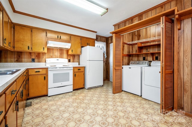 kitchen featuring white appliances, sink, wooden walls, washer and dryer, and ornamental molding