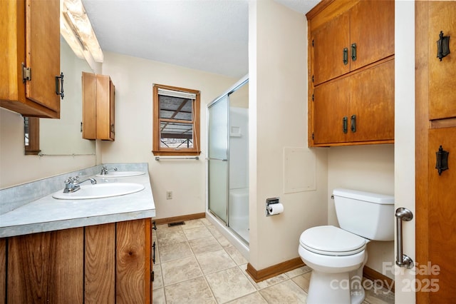 bathroom with tile patterned floors, vanity, toilet, and a shower with shower door