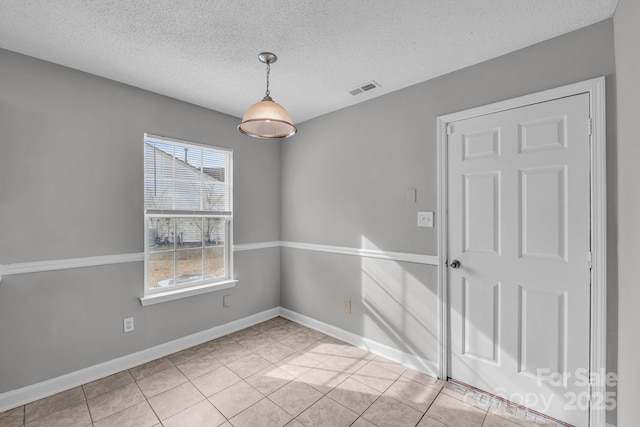 empty room featuring a textured ceiling, baseboards, visible vents, and light tile patterned floors