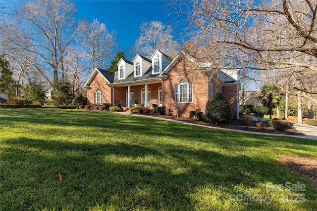 new england style home featuring a front yard and covered porch