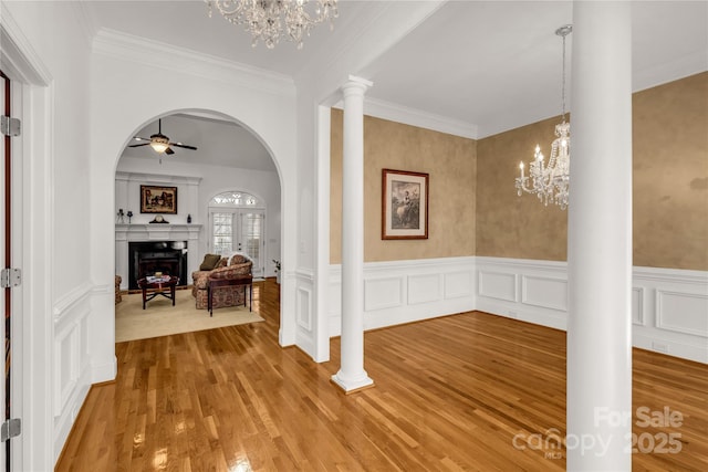 hall featuring hardwood / wood-style floors, an inviting chandelier, crown molding, and ornate columns