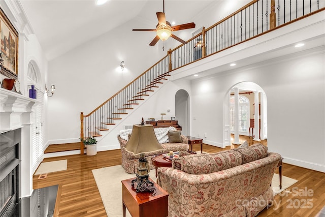 living room featuring hardwood / wood-style floors, high vaulted ceiling, ceiling fan, and crown molding