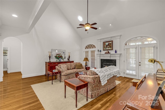 living room with ceiling fan, light hardwood / wood-style flooring, high vaulted ceiling, and french doors