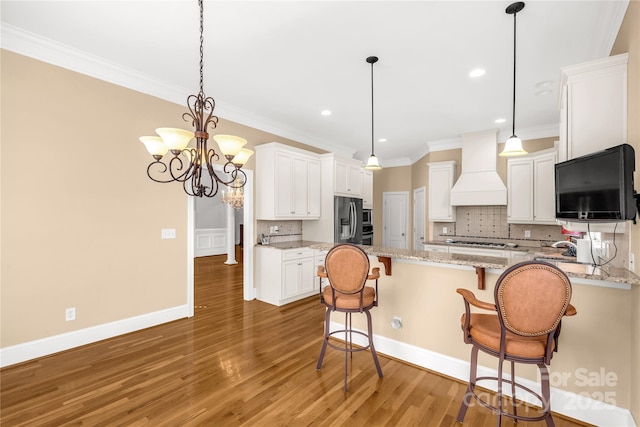 kitchen featuring premium range hood, white cabinets, tasteful backsplash, stainless steel appliances, and a chandelier