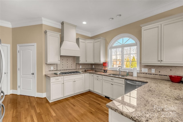 kitchen with light stone countertops, sink, white cabinets, custom exhaust hood, and appliances with stainless steel finishes