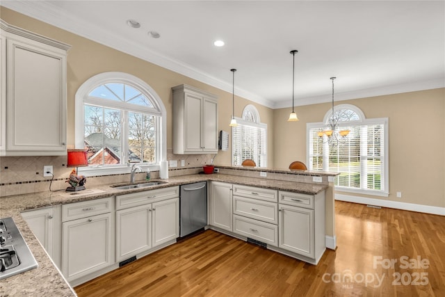 kitchen featuring pendant lighting, sink, decorative backsplash, ornamental molding, and kitchen peninsula