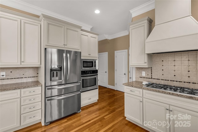 kitchen featuring backsplash, stainless steel appliances, custom range hood, and ornamental molding