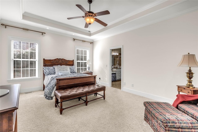 carpeted bedroom featuring ceiling fan, a raised ceiling, crown molding, and ensuite bath