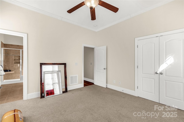 unfurnished bedroom featuring carpet flooring, ceiling fan, ensuite bathroom, a closet, and ornamental molding