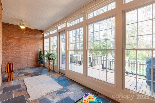 unfurnished sunroom featuring ceiling fan and a healthy amount of sunlight