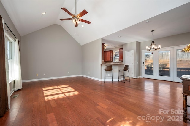 unfurnished living room with ceiling fan with notable chandelier, dark hardwood / wood-style floors, and a wealth of natural light