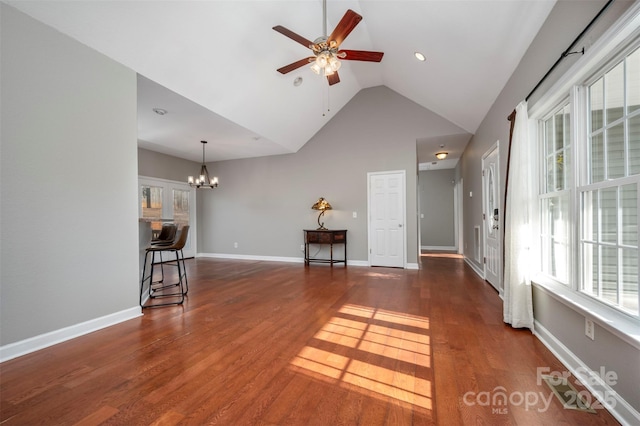 unfurnished living room with ceiling fan with notable chandelier, lofted ceiling, and dark wood-type flooring