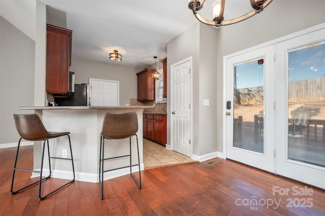 kitchen with kitchen peninsula, a kitchen bar, tasteful backsplash, a notable chandelier, and hanging light fixtures