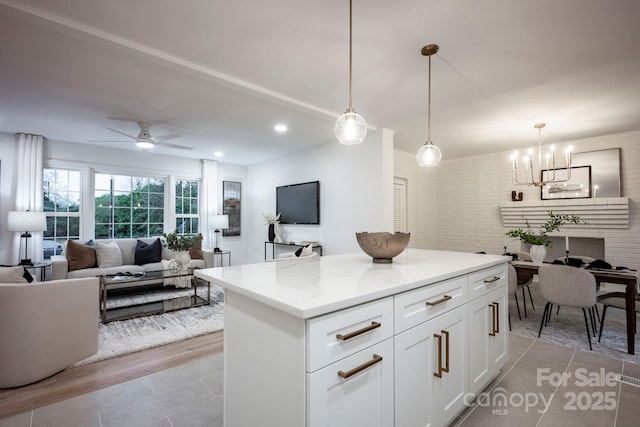 kitchen with light stone counters, white cabinetry, pendant lighting, a kitchen island, and ceiling fan