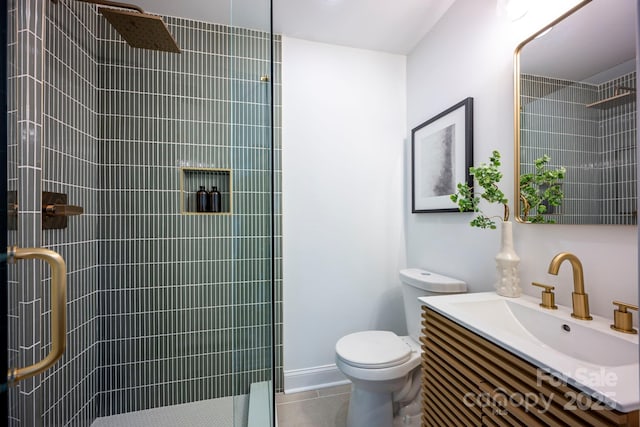 bathroom featuring a shower with shower door, vanity, tile patterned flooring, and toilet