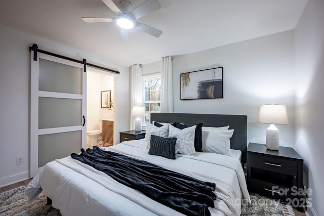 bedroom featuring ceiling fan, ensuite bath, and a barn door