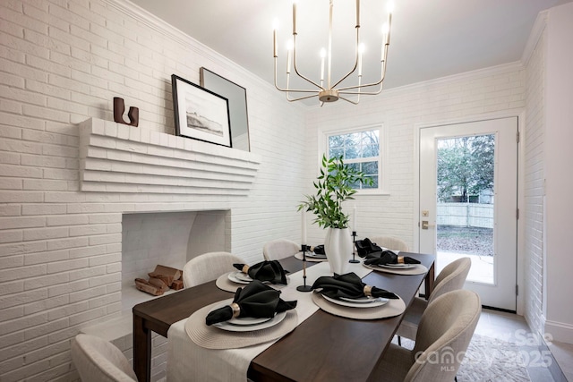 dining room featuring an inviting chandelier, brick wall, and ornamental molding