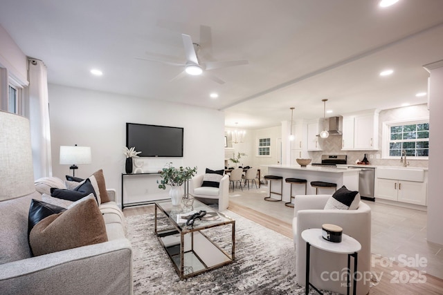 living room featuring sink and ceiling fan with notable chandelier