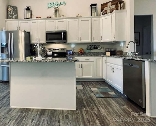 kitchen with white cabinets, dark hardwood / wood-style floors, dark stone countertops, and stainless steel appliances