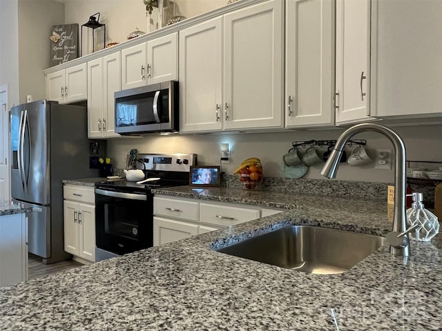 kitchen featuring light stone countertops, white cabinetry, sink, and appliances with stainless steel finishes