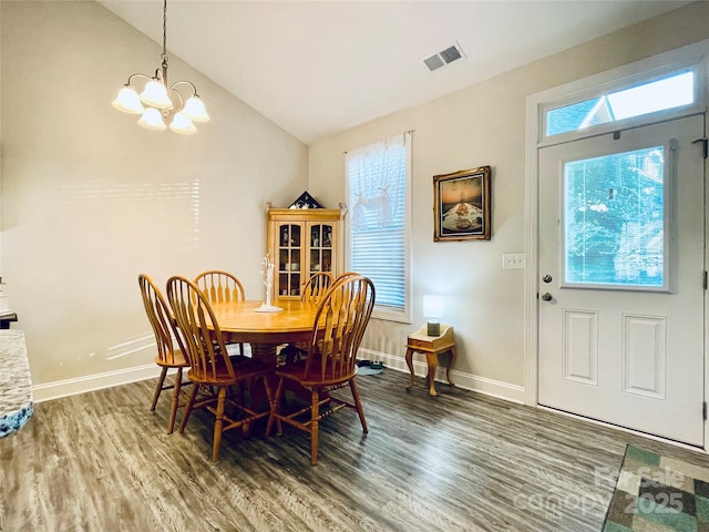 dining room featuring hardwood / wood-style flooring, vaulted ceiling, and a notable chandelier