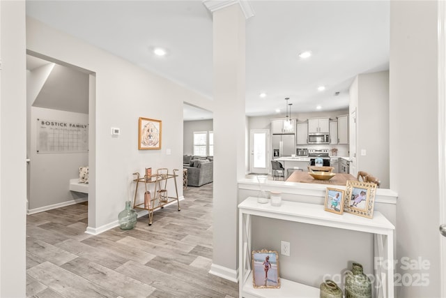 kitchen featuring light hardwood / wood-style floors, kitchen peninsula, hanging light fixtures, and appliances with stainless steel finishes