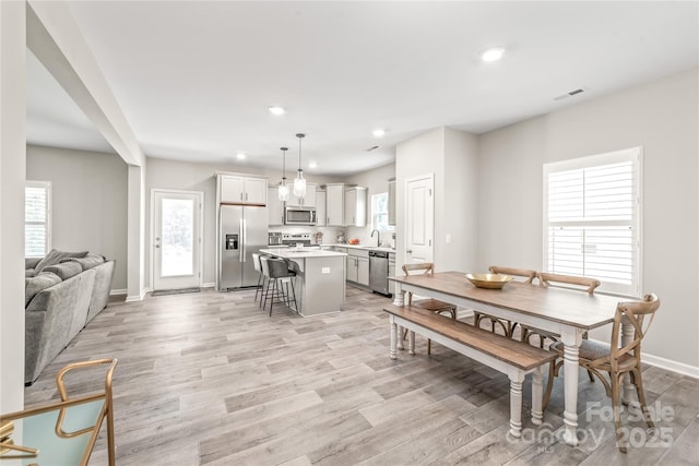 dining area featuring sink, plenty of natural light, and light wood-type flooring