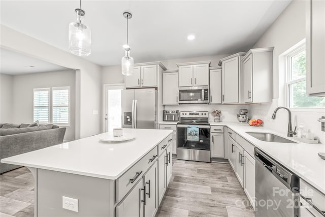 kitchen with a center island, sink, hanging light fixtures, stainless steel appliances, and decorative backsplash