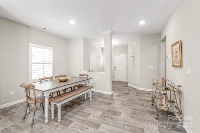 dining area featuring light wood-type flooring and decorative columns