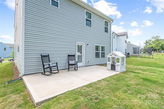 back of property featuring a patio area, a trampoline, and a yard