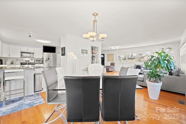 dining space with light hardwood / wood-style flooring and a notable chandelier